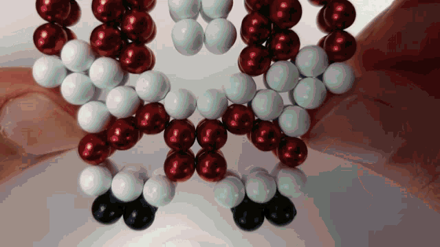 a string of red white and black beads is being held by a person