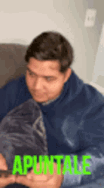 a blurry picture of a man sitting on a couch with the word apuntale in green letters .