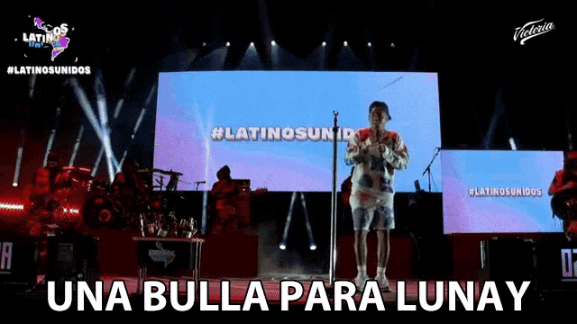 a man singing into a microphone on a stage with the words una bulla para lunay written on the bottom