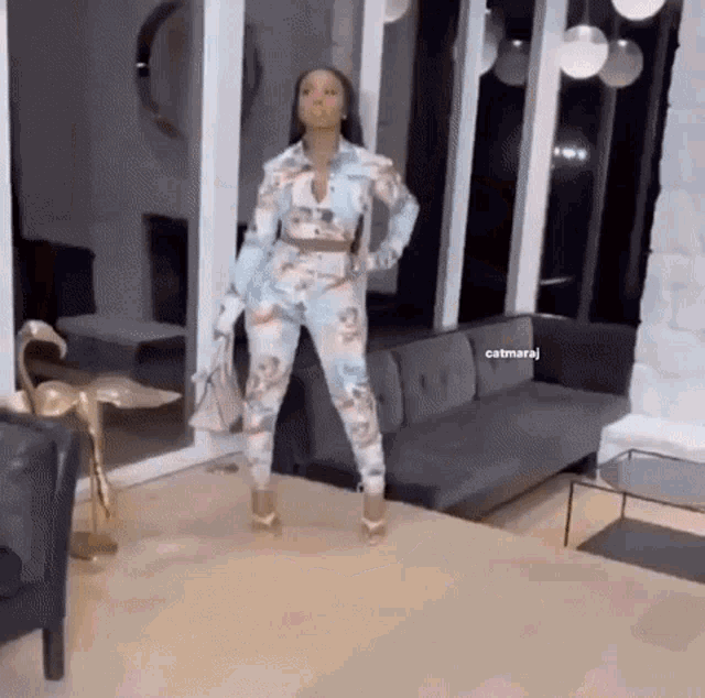 a woman is standing in a living room next to a couch and a table .