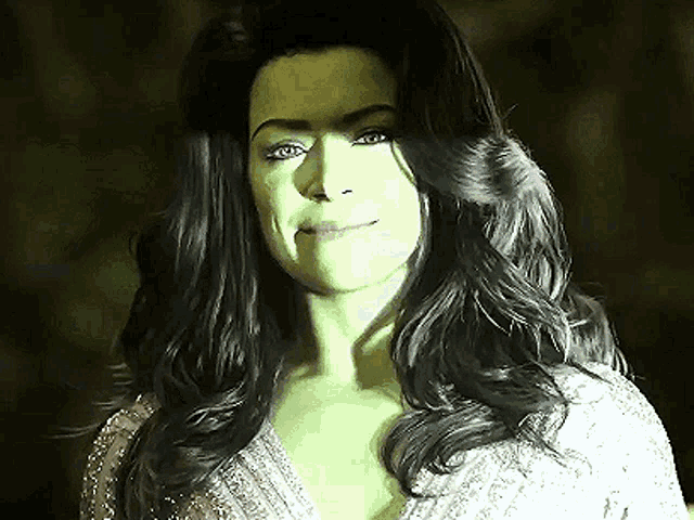 a woman with green hair and black hair is wearing a white dress and smiling .