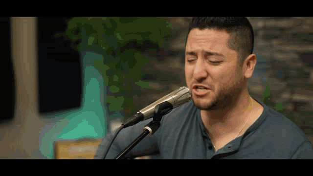 a man singing into a microphone with his eyes closed and his mouth open