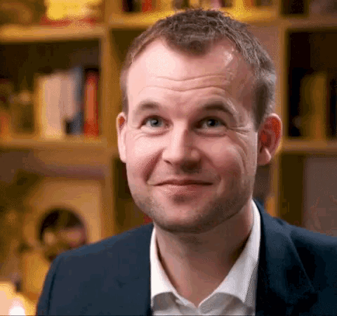 a man in a suit and white shirt looks at the camera