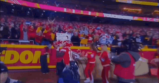 a football player is running in front of a crowd holding a sign that says ' gdom ' on it .