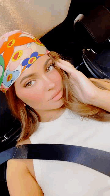 a woman wearing a headband with flowers on it is sitting in a car
