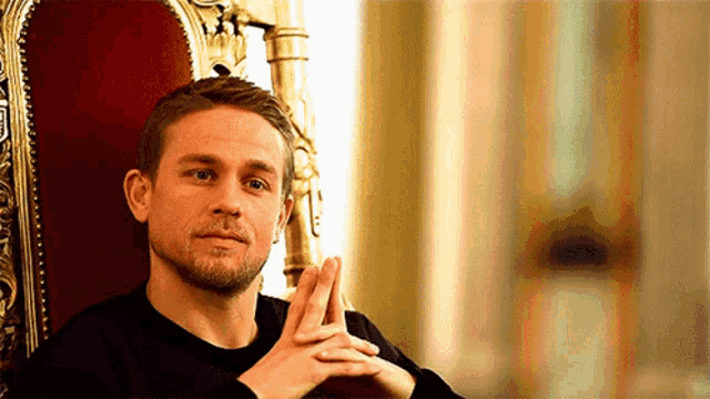 a man is sitting in a chair with his hands folded in front of his face .