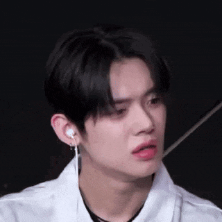 a close up of a young man wearing a white shirt and earrings .