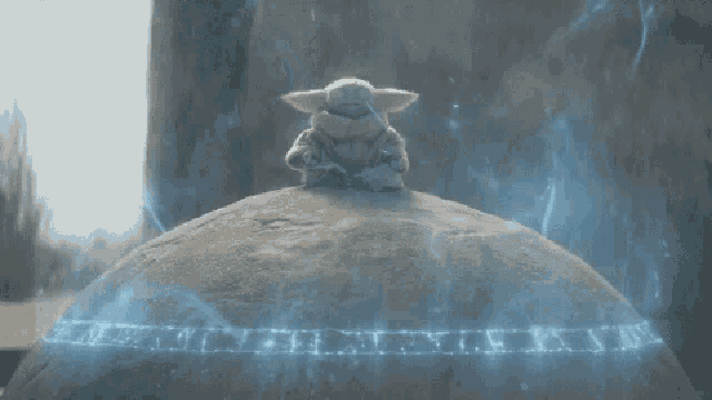 a baby yoda sits on top of a large rock surrounded by blue smoke