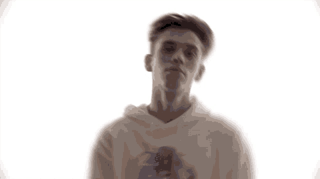 a young man in a white hoodie is looking at the camera
