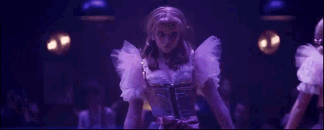 a woman in a purple dress is dancing in front of a crowd of people .