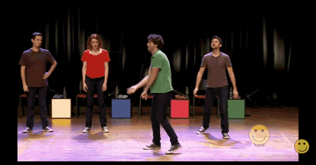 a group of people are dancing on a stage with a smiley face in the background