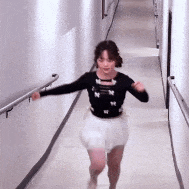 a woman in a white skirt is running down a hallway .