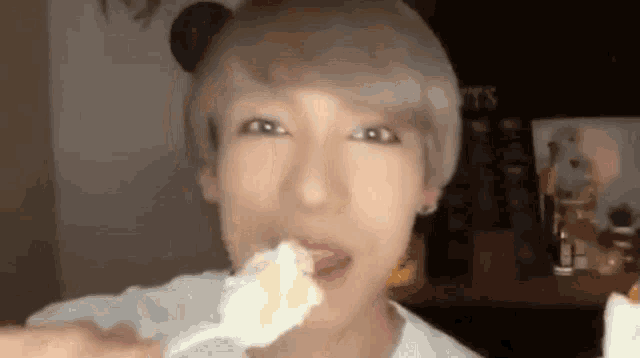 a young man with blonde hair is eating a piece of cake .