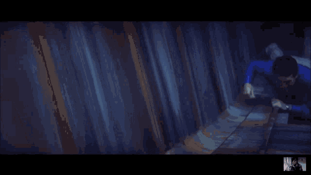a man in a blue shirt is crawling through a tunnel