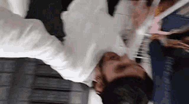 a man in a white shirt and tie is laying on his back on a table .
