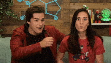 a man in a red leather jacket and a woman in a red t-shirt are sitting on a couch