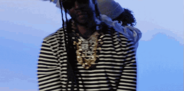 a man wearing a black and white striped shirt and gold necklace