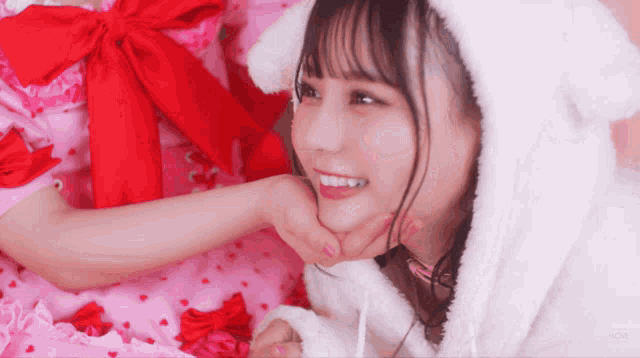 a girl wearing a white furry hood with ears and a red bow