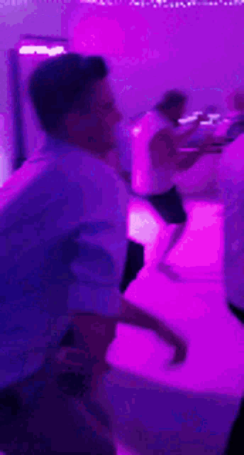 a group of people are dancing in front of a purple light .