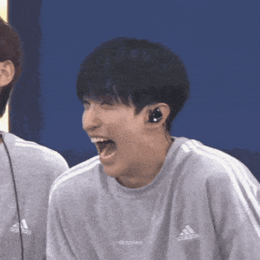 a man wearing a grey adidas sweatshirt is laughing