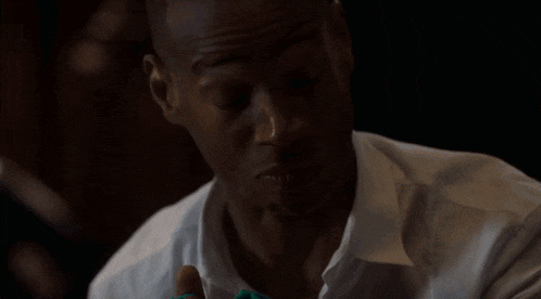 a man in a white shirt has his arm outstretched in the dark