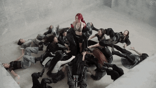 a woman with red hair is surrounded by a group of dancers wearing black and white