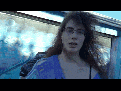 a woman wearing glasses and a blue shirt is standing in front of a window that says ' sydney ' on it
