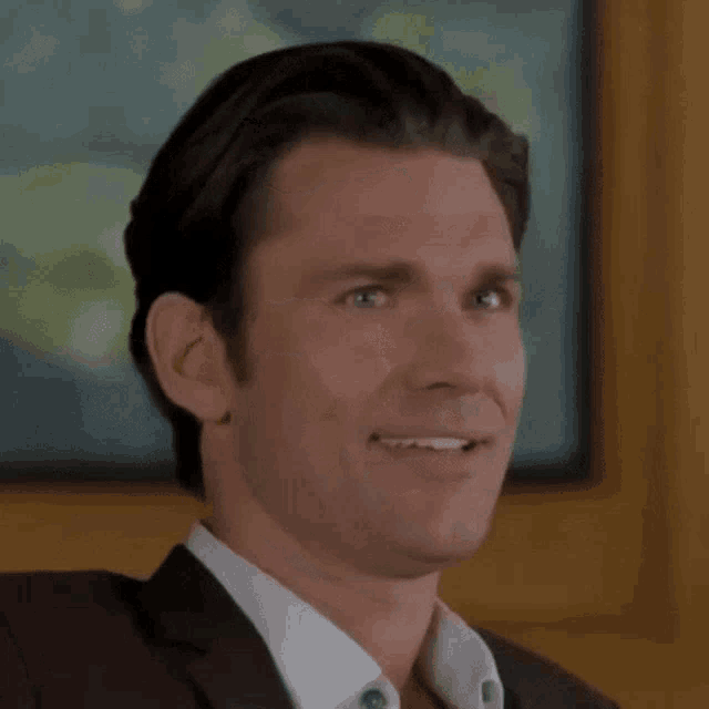 a man in a suit and white shirt is smiling and looking at the camera .