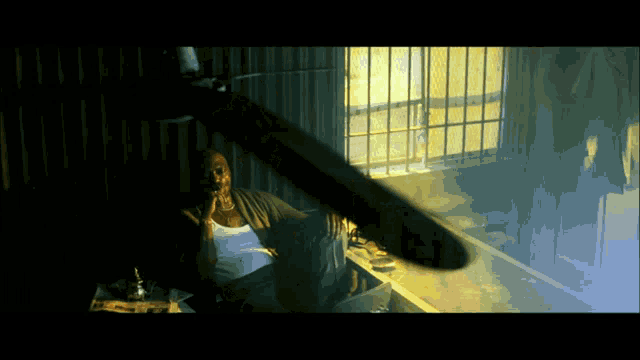 a man is sitting in a dark room with a knife flying in the air