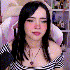 a woman in a striped shirt is sitting in a pink chair and talking into a microphone .