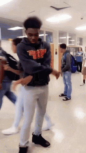 a boy wearing a hoodie with the letter w on it is standing in a hallway