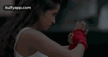 a woman is wrapping her hands in red boxing wraps and ready to fight .