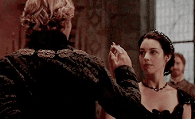 a woman in a black dress is holding the hand of a man in a black jacket .