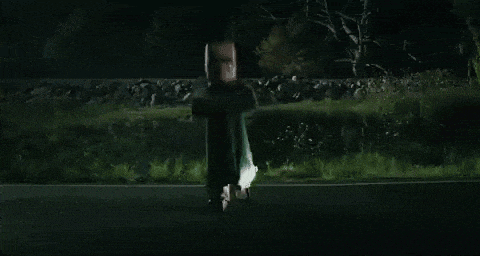 a person is flying through the air in front of a car in the dark .