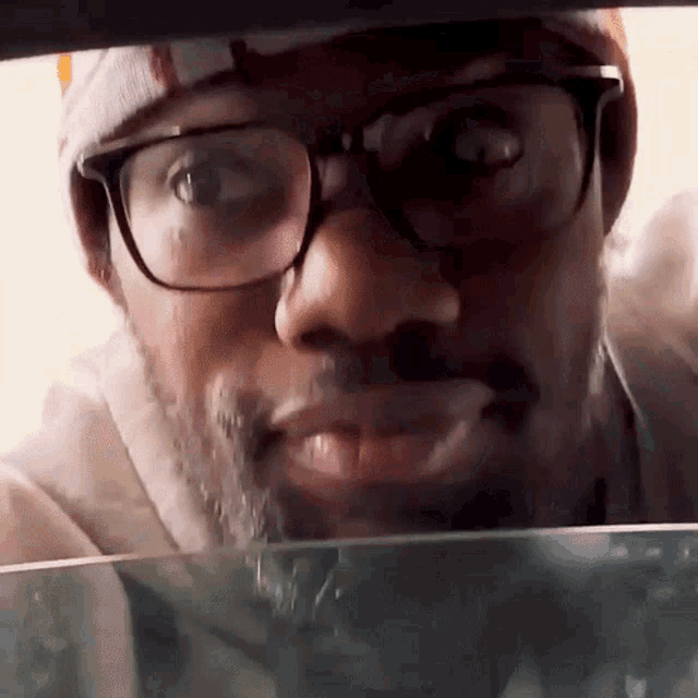 a man with glasses and a beard is looking through the windshield of a car