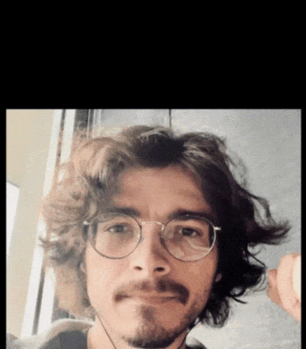 a man with glasses and a beard is making a funny face