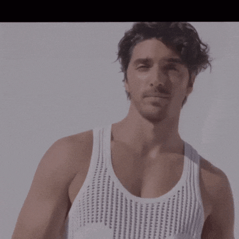 a man with a beard is wearing a white knitted tank top