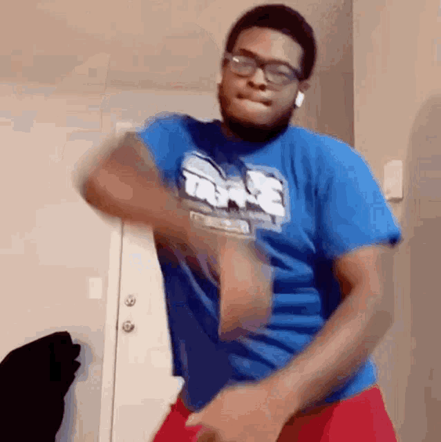 a man wearing a blue shirt and red shorts is dancing .