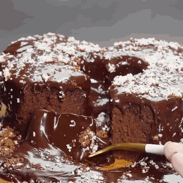 a person is taking a piece of chocolate cake with powdered sugar