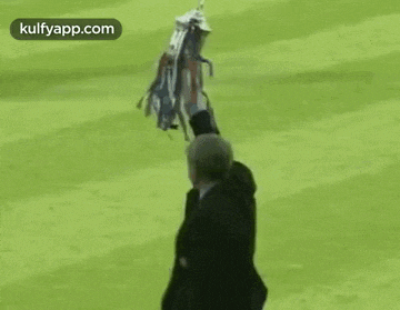 a man in a suit is holding a bouquet of flowers in his hand on a soccer field .