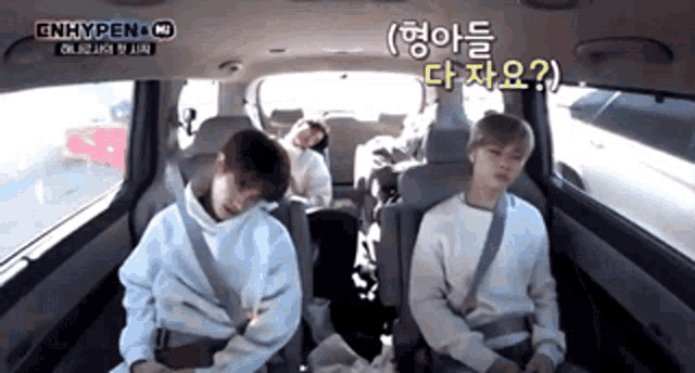 a group of people are sitting in the back seat of a car with korean writing on the screen .