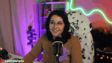a woman sitting in front of a microphone with lochvaness on the bottom right