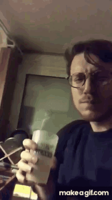 a man wearing glasses is holding a cup that says ' a ' on it