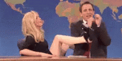 a man and a woman are sitting at a desk with a woman 's leg up .