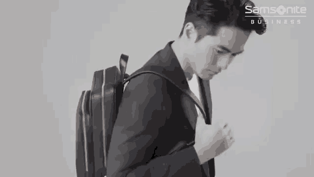 a man in a suit carrying a samsonite business backpack