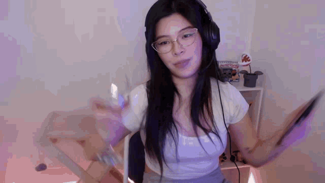 a woman wearing headphones and glasses is standing in a room holding a tablet .