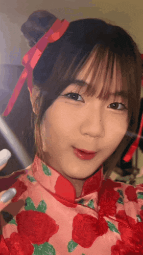 a girl wearing a pink dress with red roses and a red ribbon in her hair