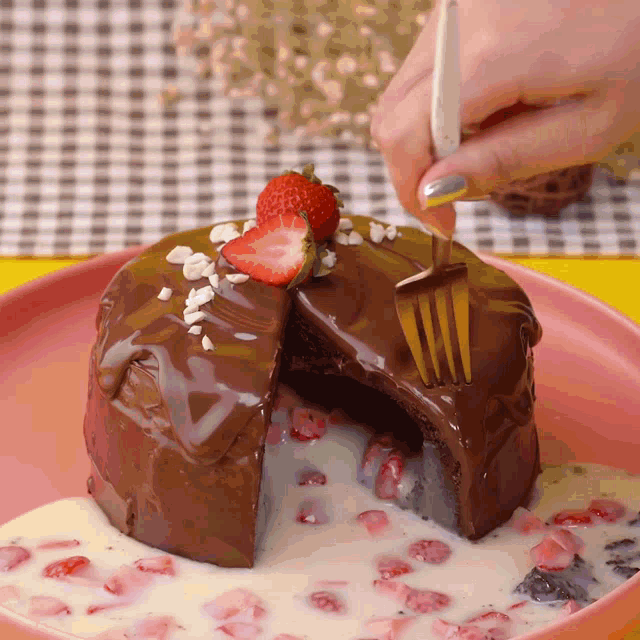 a person is taking a slice of chocolate cake with strawberries on top with a fork