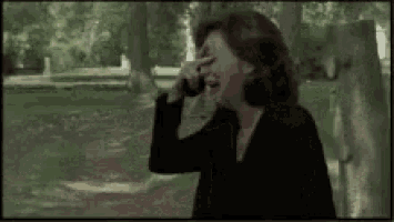 a woman in a black jacket is laughing while covering her face with her hand .