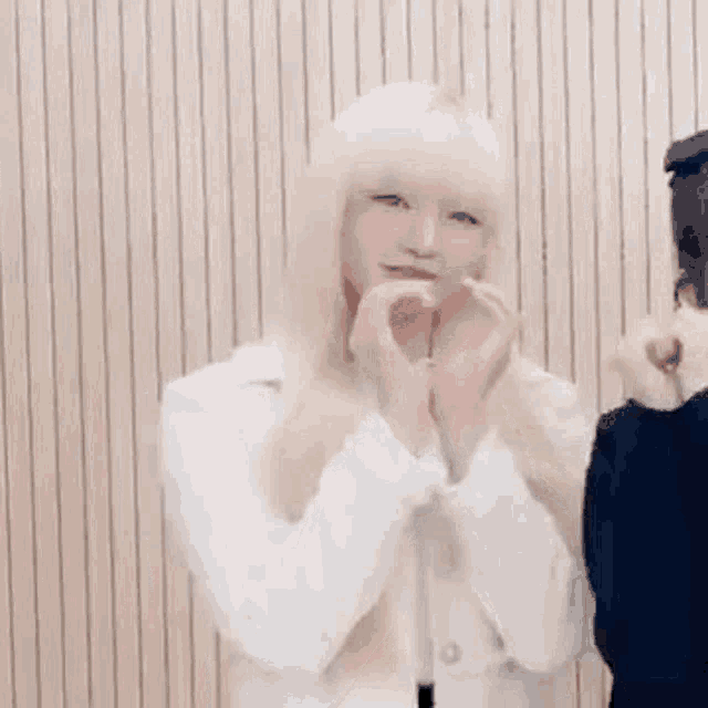 a girl with blonde hair is making a heart shape with her hands .